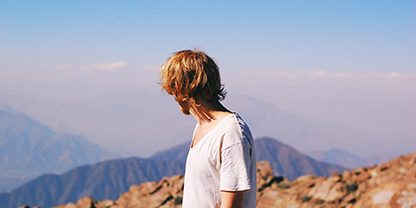 Young Man Looking Back At A Mountain Top